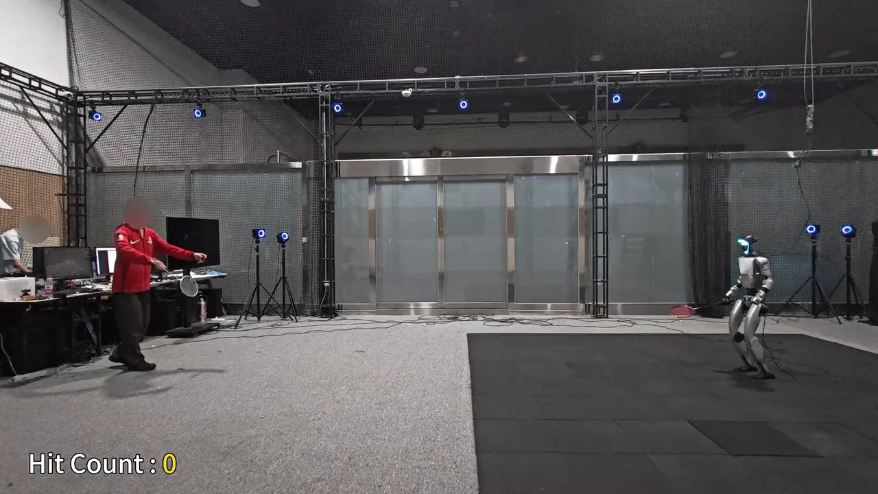 A still from the lab's rally footage: a person in a red shirt, face blurred, rallies with the humanoid robot across the room, with the lab's hit counter in the corner.